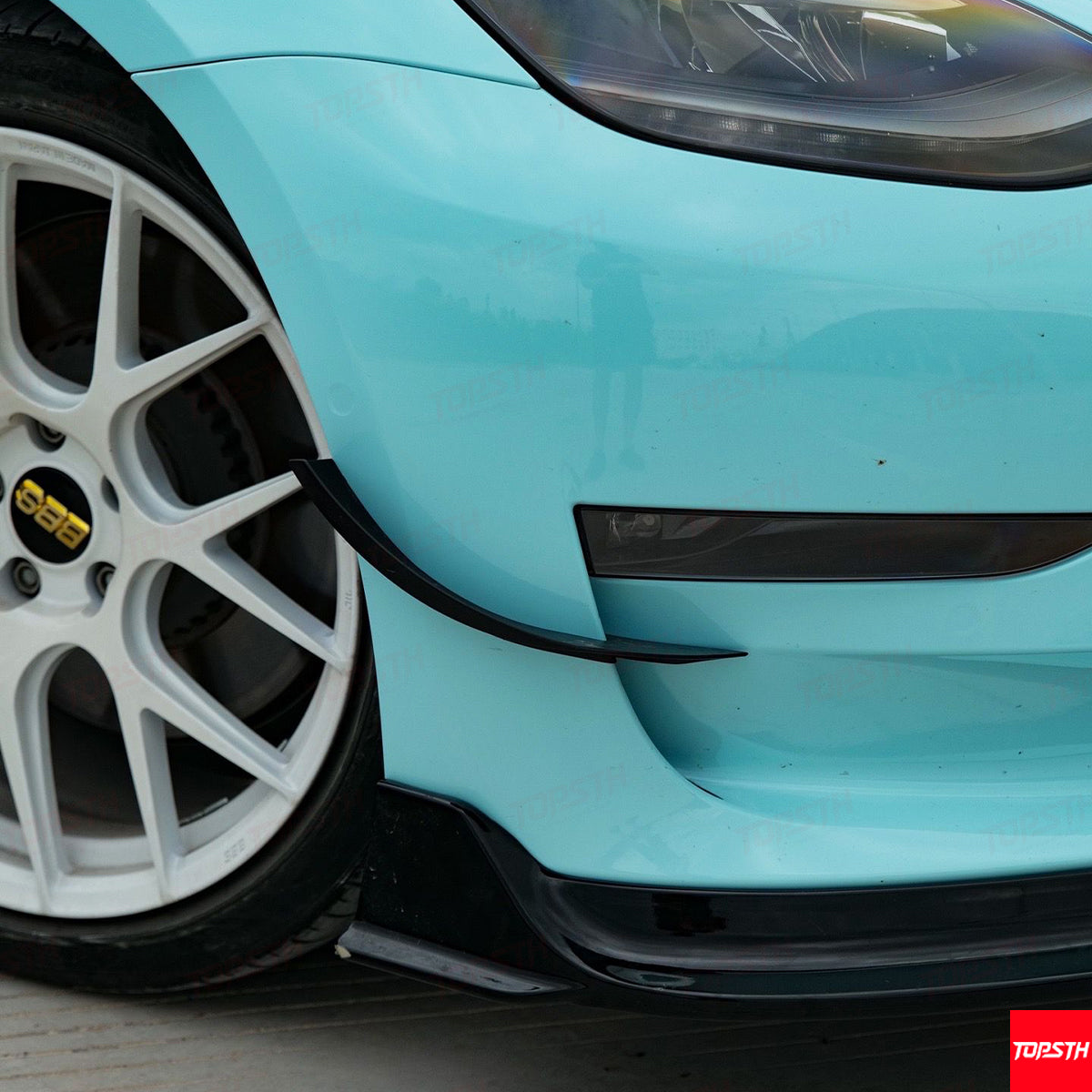 Close-up shot of the front lip spoiler and bumper splitter on a Tesla Model 3.