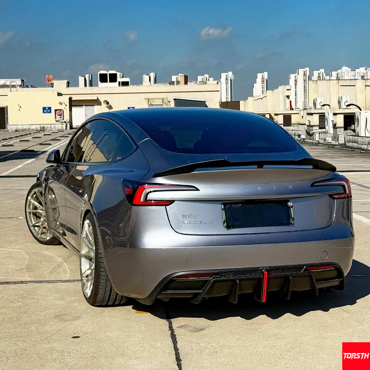 Rear perspective of Tesla Model 3 Highland showcasing the aggressive ABS rear diffuser and trunk wing.