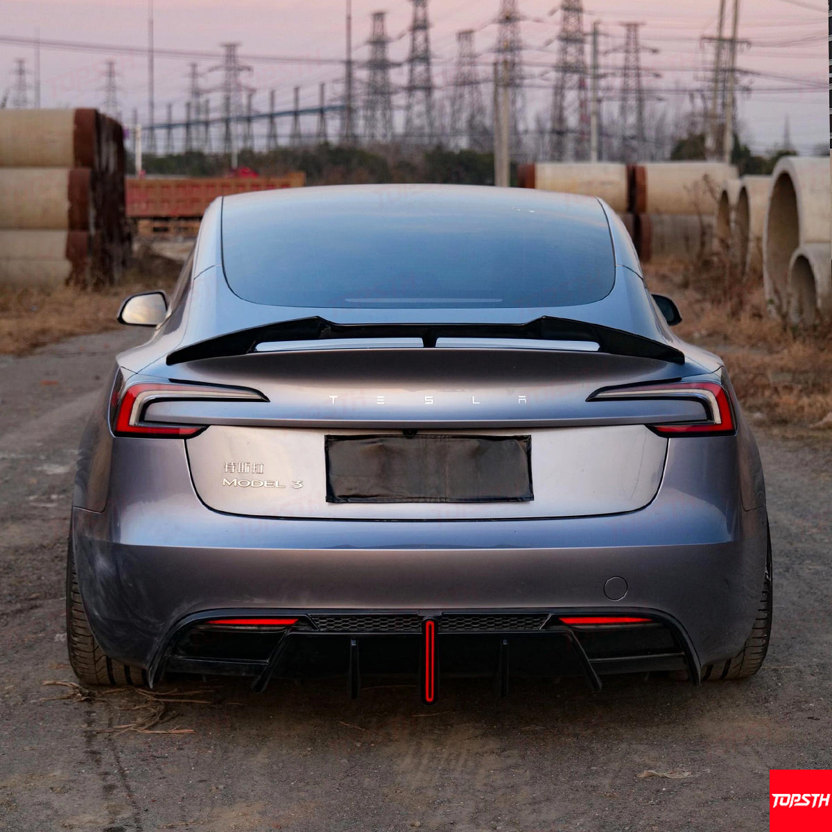 Direct rear view of Tesla Model 3 Highland highlighting the ABS diffuser with a central red racing stripe.