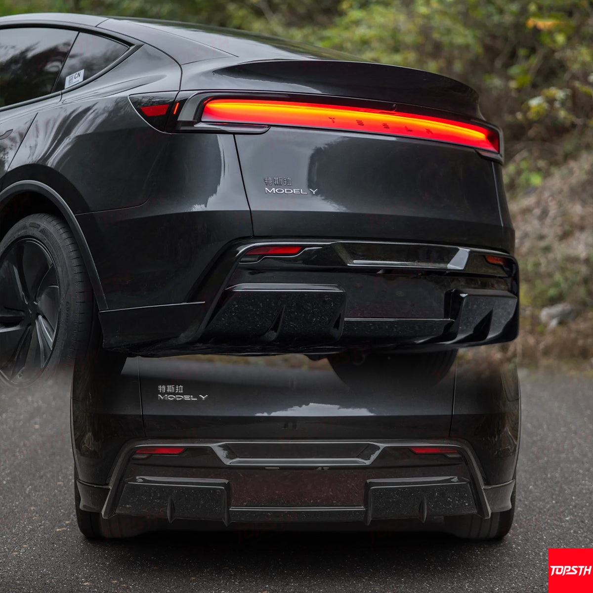 Close-up detail of a Tesla Model Y upgraded rear LED taillight system and carbon fiber style diffuser.