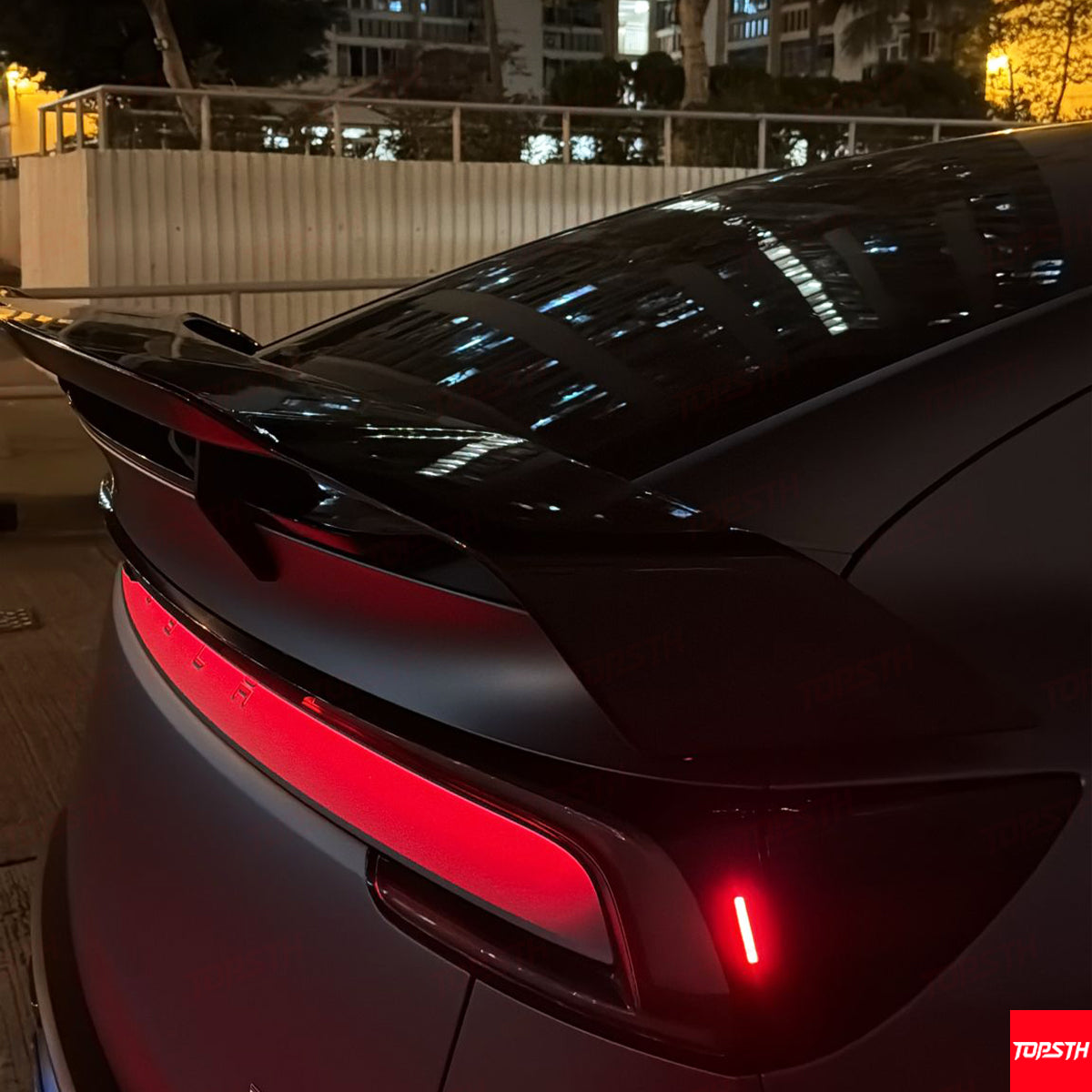 Matte black Tesla Model Y customized with an aerodynamic carbon fiber spoiler and LED light bar.